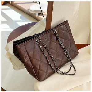 Close-up of a large dark brown tote bag with diamond quilting and leather chain strap
