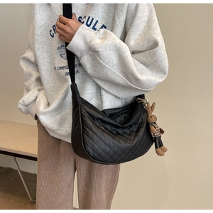 Détail du sac croissant noir en nylon matelassé avec un charmant lapin en peluche