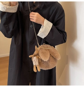 Detail of plush brown crossbody bag with gold chain strap and cute bunny pendant charm