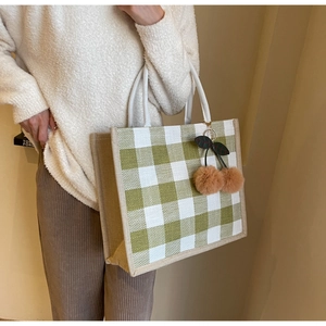 Detail of green and white checkered woven tote bag with cute brown cherry charms