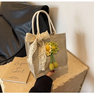 Detail of jute tote bag with lace bow, crochet flower charms and cotton rope handles