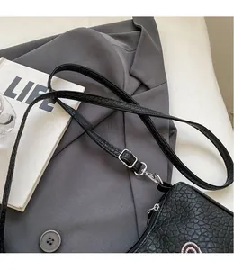 Détail de la bandoulière réglable en cuir noir avec boucle argentée sur un sac baguette chic