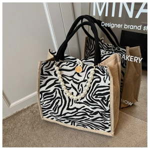 Detail of zebra print tote bag with white pearl chain and wooden button closure