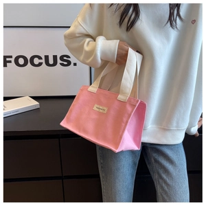 Détail d'un cabas en toile rose avec poignées tissées et écusson logo tendance