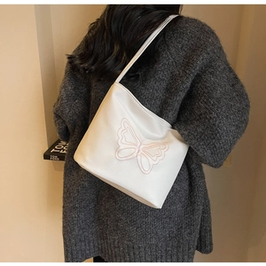 Close-up of white tote bag with pink butterfly embroidery on textured lychee leather