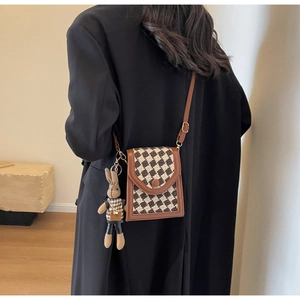 Detail of vintage houndstooth crossbody phone bag with a cute plush bunny charm