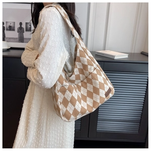 Detail of checkered canvas shoulder bag featuring a brown leather Fashion logo tag