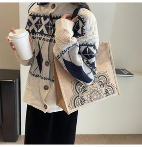 Linen tote bag with black mandala print shown with casual knit cardigan on a model