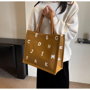 Close-up of yellow canvas tote bag with white lettering showing fabric texture and strap