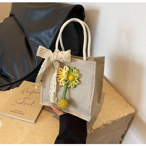 Detail of jute tote bag featuring crochet sunflowers and delicate lace bow charm