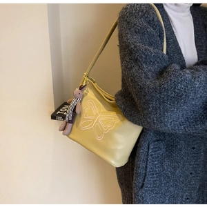 Detail of yellow pebbled leather tote bag with butterfly embroidery and plush bunny charm