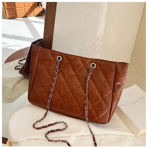 Close-up of brown quilted tote bag featuring vintage leather texture and silver chain strap