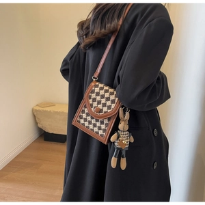Chic checkered crossbody bag with cute rabbit pendant shown on a model's shoulder
