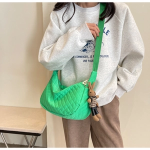 Détail du sac hobo matelassé vert vif avec breloque lapin porté par un mannequin