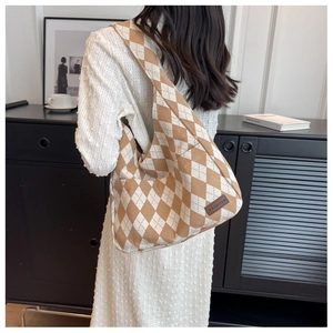 Detail of vintage canvas shoulder bag featuring brown argyle pattern and fashion leather tag