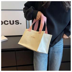 Détail d'un sac cabas en toile avec poignées roses porté par un mannequin