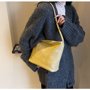 Detail of yellow pebbled leather tote bag with white butterfly embroidery and slim strap