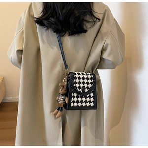 Rear view of a mini black crossbody bag with checkerboard pattern and bunny charm accessory