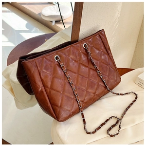 Close-up of brown quilted leather tote bag with silver chain strap and metal eyelet details