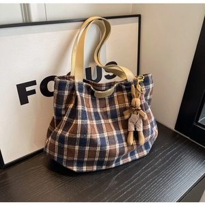 Detail of wool tote bag with classic plaid pattern and cute plush bunny charm