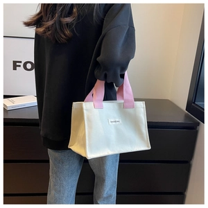 Détail du sac cabas en toile avec poignées tissées roses et étiquette de mode