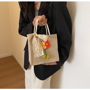 Close-up of linen lunch tote bag with white lace bow and floral charm detail