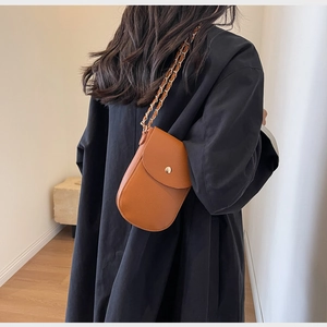 Detail der orangefarbenen Mini-Umhängetasche aus Leder mit geflochtenem Kettenriemen