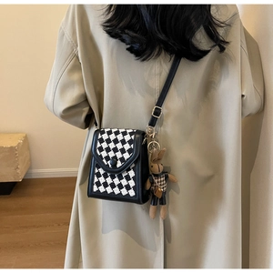 Detail of checkered crossbody phone bag with a cute brown rabbit charm and leather strap