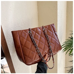 Detailed close-up of brown quilted faux leather tote bag with silver chain strap