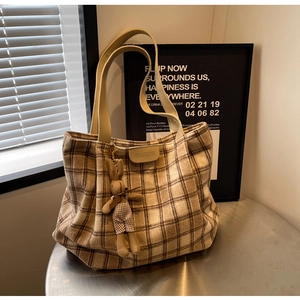 Detail of plaid wool tote bag featuring a cute rabbit charm and fashion label tag