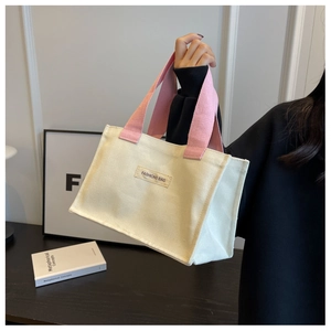 Détail du sac fourre-tout en toile crème avec anses roses et étiquette de mode