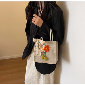 Detail of linen tote bag with white lace bow and 3D woven flower pendant charm