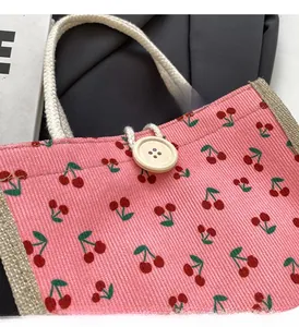 Detail of pink corduroy tote bag with cherry pattern and natural wooden button closure