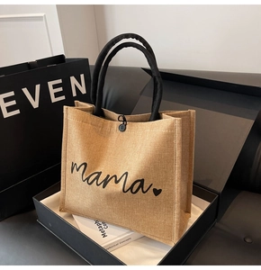 Close-up of linen tote bag with black mama script text in an elegant gift box setting