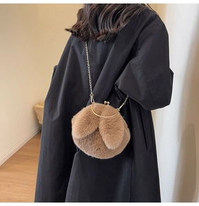 Brown plush rabbit bag with long ears and chain strap shown on black coat