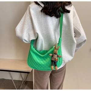 Détail du sac hobo vert matelassé avec pendentif lapin porté par un mannequin