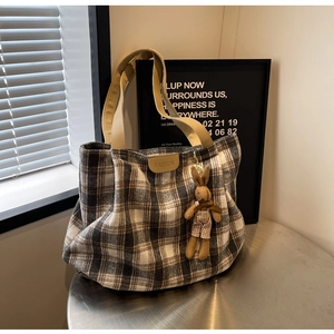Detail of brown plaid canvas tote bag featuring fashion label and cute bunny charm pendant