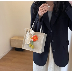 Close-up of linen handbag with lace bow and woven floral charm in a minimalist interior