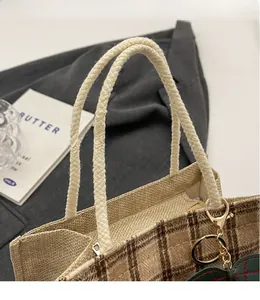 Detail of vintage plaid tote bag with woven rope handles and gold hardware accents