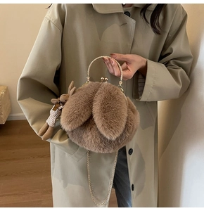 Detail of plush rabbit crossbody bag with golden handle and cute bunny charm pendant