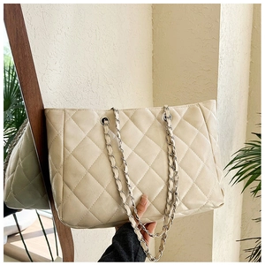 Detail of the cream quilted tote bag with silver chain strap and shiny faux leather texture
