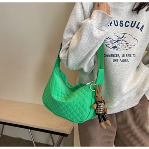 Détail du sac croissant matelassé vert vif avec un pendentif lapin en peluche marron