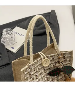 Detail of woven plaid handbag featuring large wooden button closure and green leaf charm