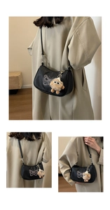 Détail du sac hobo noir avec broderie papillon et breloque en peluche sur cuir texturé