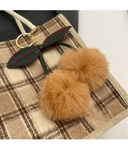 Creative plush cherry charm with golden metal clasp attached to a checkered handbag