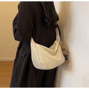 Détail du sac hobo matelassé crème avec large bandoulière et pendentif lapin sur modèle