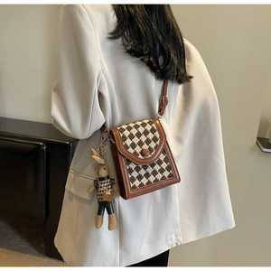 Brown checkerboard crossbody bag with cute rabbit charm detail on beige blazer