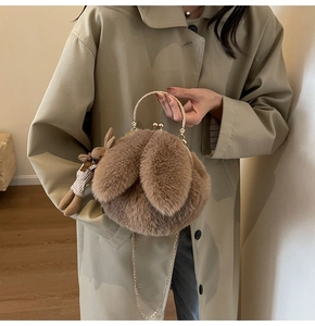Detail of plush brown rabbit bag with golden handles, chain strap and cute doll pendant