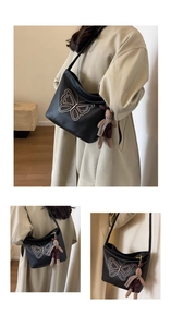 Detail of black pebbled leather tote featuring pink butterfly embroidery and rabbit charm