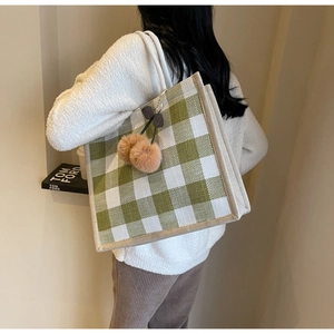 Detail of green and white waffle knit tote bag with plush cherry charm on shoulder